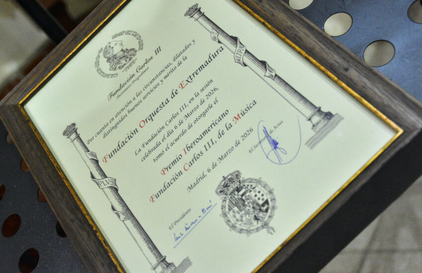 Framed award certificate with stamps and signatures angled on a wooden frame surface.